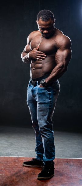 A portrait of a hot handsome strong afro american guy man without a shirt against dark background. Studio photo. Male beauty concept. Closeup. - Foto, Imagen