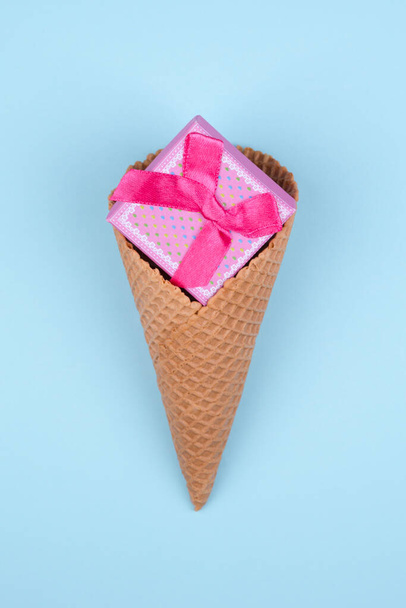 Roze geschenkdoos in ijskegel op lichtblauwe achtergrond. Minimaal Valentijnsdag concept. - Foto, afbeelding