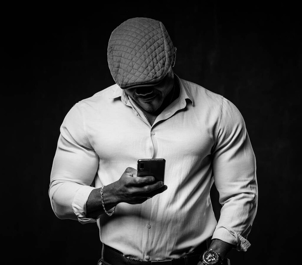 Black and white portrait of stylish unrecognizible african american with head down looking at phone. Closeup. - Photo, Image