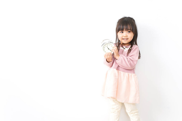 Милая маленькая девочка с будильником - Фото, изображение