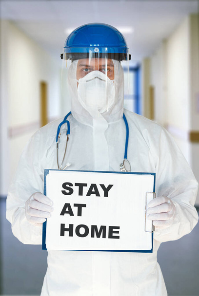 Male doctor holding a tablet with paper with the words stay at home, calls for quarantine and non-proliferation of a dangerous novel coronavirus or covid-19 - Foto, immagini