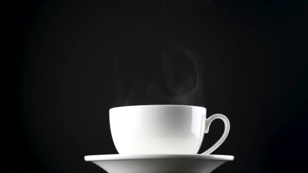 Hot drink with steam. White cup with hot coffee or tea slowly moving on an isolated black background.  Full HD video 1920x1080 - Video