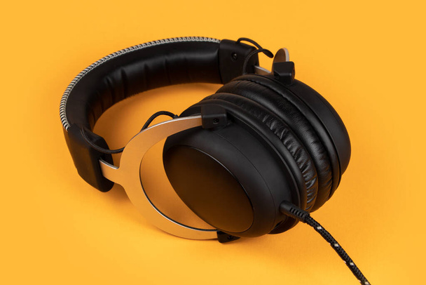 Μαύρα ακουστικά σε κίτρινο φόντο. Μουσική έννοια. - Φωτογραφία, εικόνα