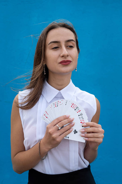 naispuolinen pelaaja, jolla pokerikortit eristetty sinisellä taustalla. Peli - Valokuva, kuva