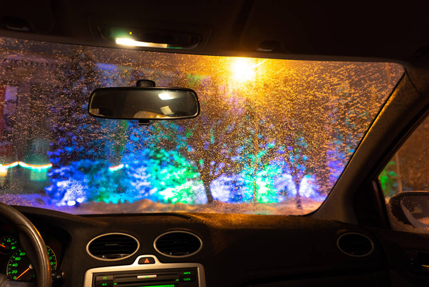 frosted car glass. snow covered car windshield. view from inside the car on the night city - Фото, зображення