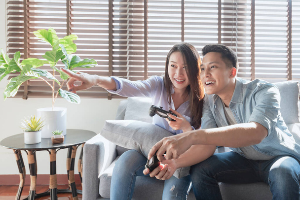 Aziatisch paar liefhebbers genieten en spelen console spel op vakantie maken meer kwaliteit tijd van geluk samen thuis - Foto, afbeelding