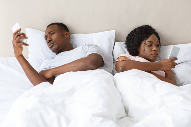 男と女がベッドに横になってスマホを使って - 写真・画像