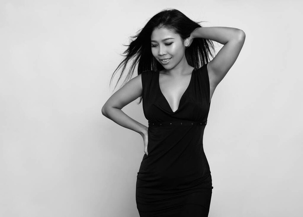 Beautiful asian woman with long black hair posing in dress on grey background - Фото, зображення