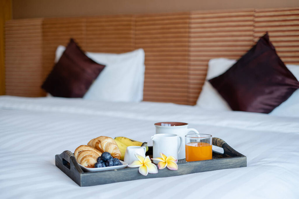 Concentra-te na fruta. Em um quarto de hotel com frutas, coloque uma bandeja na cama para receber a chegada de hóspedes VIP. - Foto, Imagem