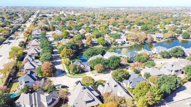 Вид сверху на престижный район рядом с местной улицей с цветными осенними листьями. Воздушный ряд жилых домов с видом на озеро в Келле, Техас, Америка. - Фото, изображение