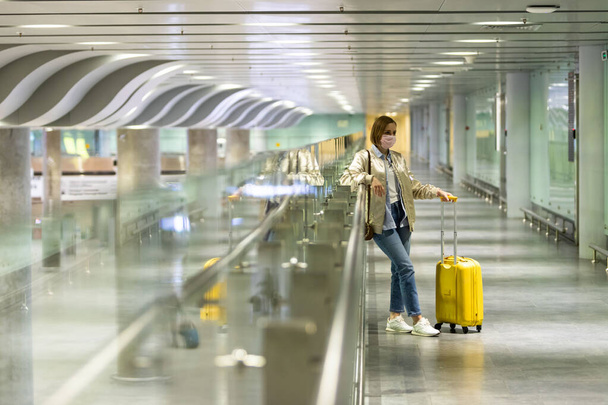 Vrouw met bagage vast op lege luchthaventerminal als gevolg van coronavirus pandemie / Covid-19 uitbraak reisbeperkingen. Vluchtannulering. Financiële crisis in de reisindustrie.Quarantaine-isolatiemaatregel - Foto, afbeelding