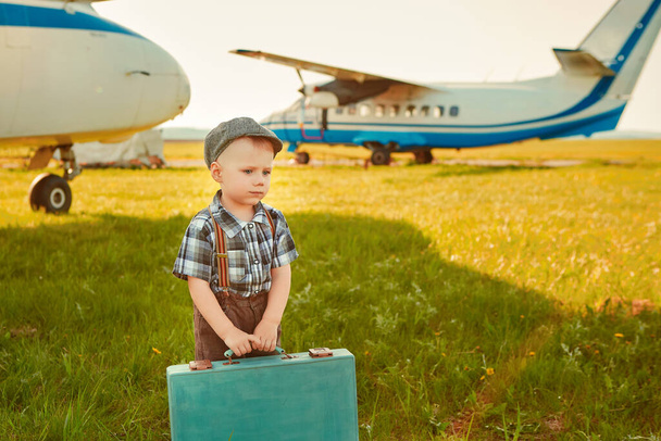 A cute little boy stands next to the propeller of an old airplane on a Sunny day - Photo, image