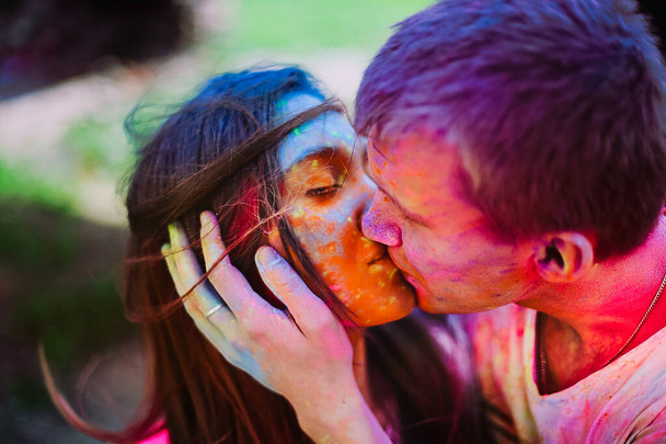 Young woman and man kissing and celebrating holi festival. Portrait of happy couple in love on holi color festival. Love and hippie lifestyle concept - Photo, image