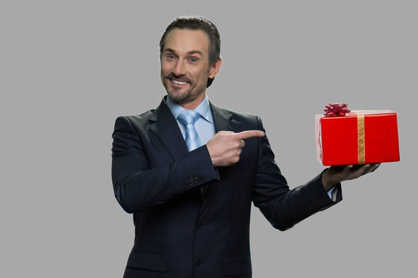 Χαμογελαστή επιχειρηματίας δείχνει κουτί δώρου στο χέρι του. - Φωτογραφία, εικόνα