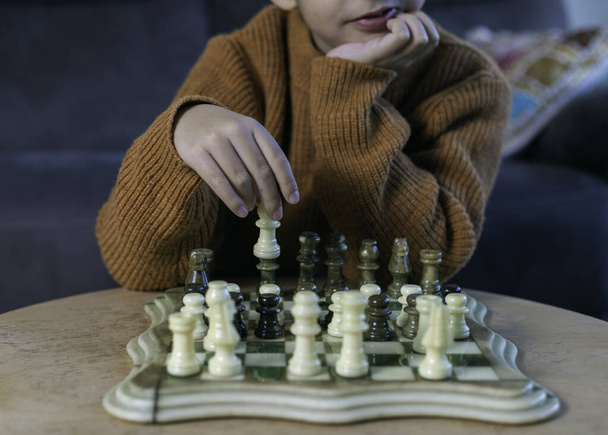 Concentrated boy plays with a green and white marble chess Conceptual of logical thinking in childhood, game, sport - Photo, Image