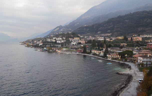Vista superior de la costa del lago de Garda, las montañas y la ciudad de Malcesine en un día nublado. - Foto, Imagen