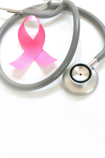 Pink ribbon and stethoscope on white background, closeup. Breast cancer awareness concept - Фото, изображение