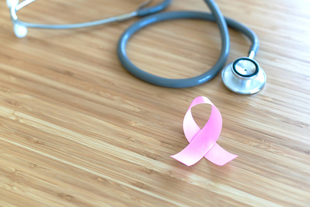 Pink ribbon and stethoscope on wooden table. Symbol of breast cancer, health care concept. Cancer day concep - Photo, image