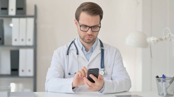 Férfi orvos használja Smartphone az irodában  - Fotó, kép
