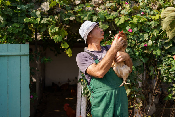 Uśmiechnięty rolnik trzymający kurczaka - Zdjęcie, obraz