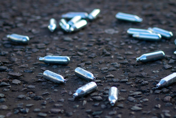 Srebrne metalowe kapsułki zawierające N2O leżą na ulicy - Zdjęcie, obraz