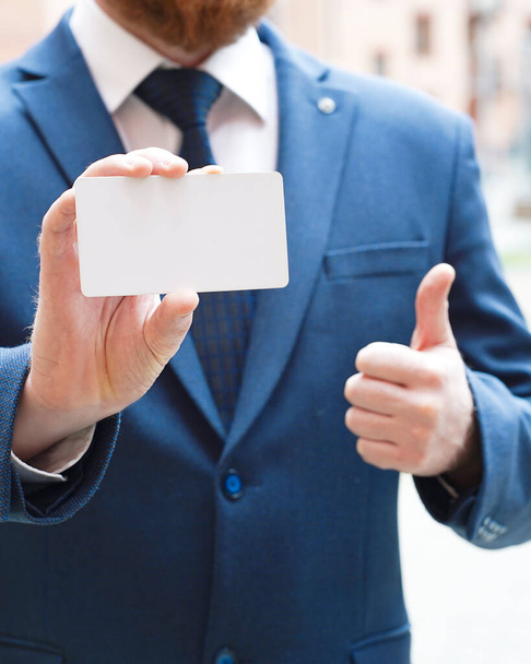 Mężczyzna trzyma w ręku białą kartkę i pokazuje znak klasy. Wysokiej jakości zdjęcie - Zdjęcie, obraz