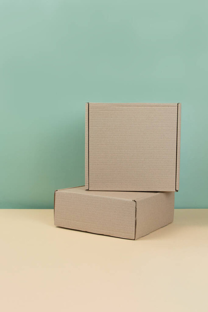 ミントの背景に茶色の段ボール箱のスタック。ブランクカートンボックス。ギフト包装の概念。ギフト用のクラフトボックスまたは中立的な背景に存在します。買い物だ。スペースのコピー. - 写真・画像