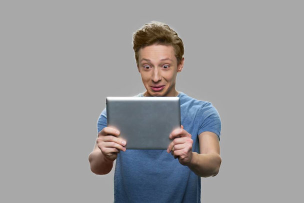 Erstaunt Teenager Junge Blick auf digitales Tablet. - Foto, Bild