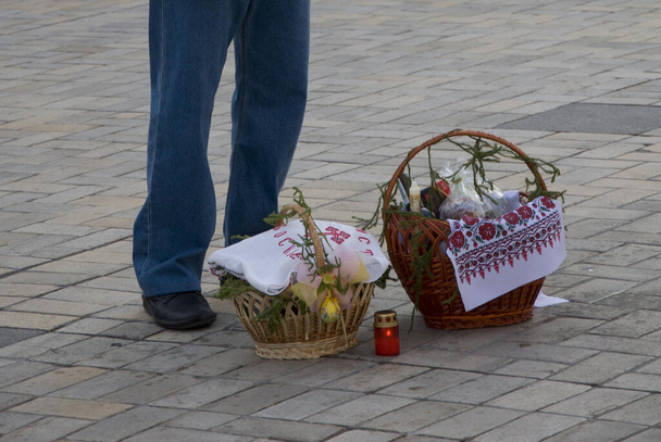 Cestas a los pies de un feligrés cerca de la iglesia con comida de Pascua para la consagración en el día de la Pascua Ortodoxa - Foto, imagen