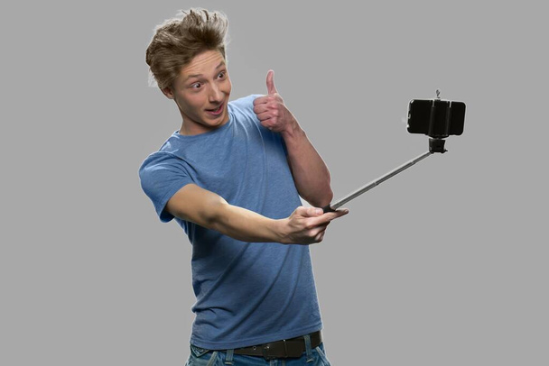 Funny teenage boy using monopod. - Foto, Imagen