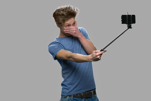 śmieszne nastolatek chłopiec biorąc selfie z selfie kij. - Zdjęcie, obraz