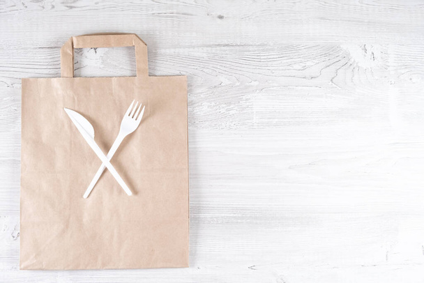 plastic fork, knife on paper bag. Eco-friendly food packaging and cotton eco bags on gray background with copy space. Carering of nature and recycling concept. containers for catering and street fast - Photo, Image