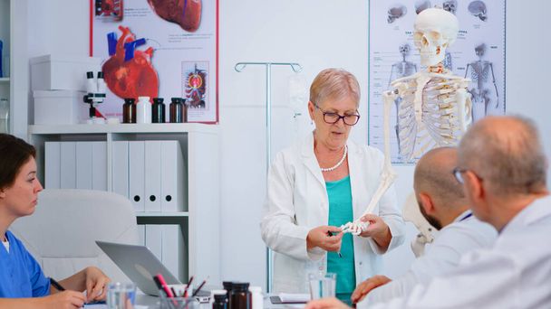 Ανώτερη γυναίκα γιατρός κρατώντας το χέρι μοντέλο σκελετού - Φωτογραφία, εικόνα