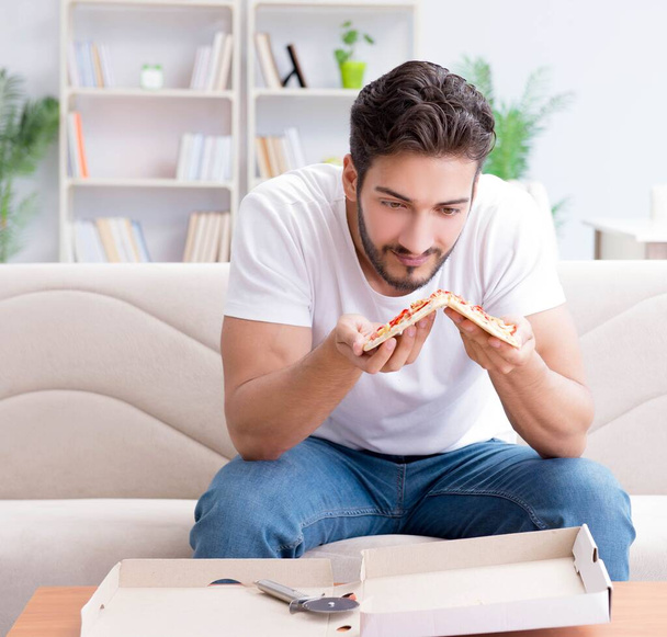 Man eating pizza having a takeaway at home relaxing resting - Foto, immagini