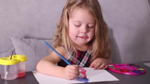 charmante petite fille blonde en robe à carreaux rouges, peinture avec des peintures colorées. enfance, art, peinture. Vidéos en Full HD - Séquence, vidéo