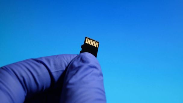 The technician worker holding in micro SD card repairing in service center on blue background. - Foto, Bild