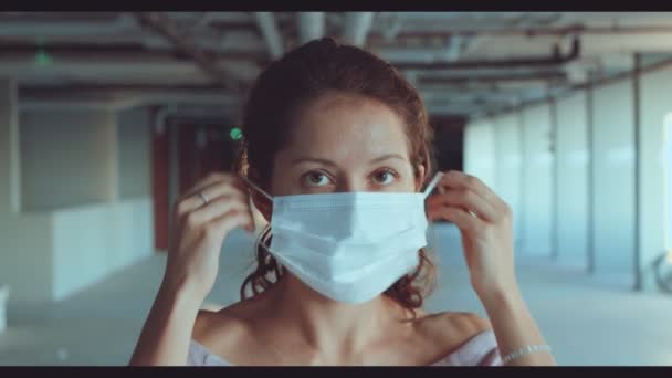 Ritratto di una giovane donna che indossa una maschera protettiva medica - Filmati, video