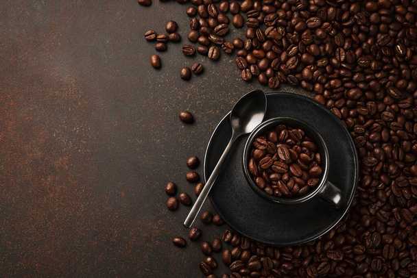 Black cup of coffee with roasted beans on a stone background. Top view with space to copy text - Fotó, kép