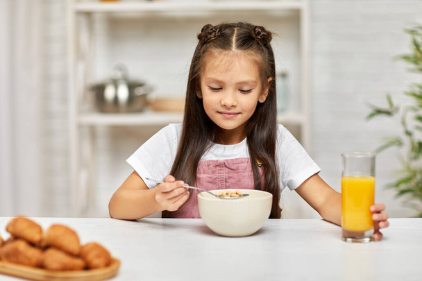 cute little child girl having breakfast - cereal and orange juice - Foto, Bild