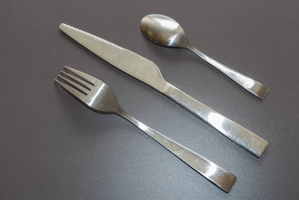 Fourchette, couteau et cuillère à café en acier inoxydable sur fond gris - Photo, image