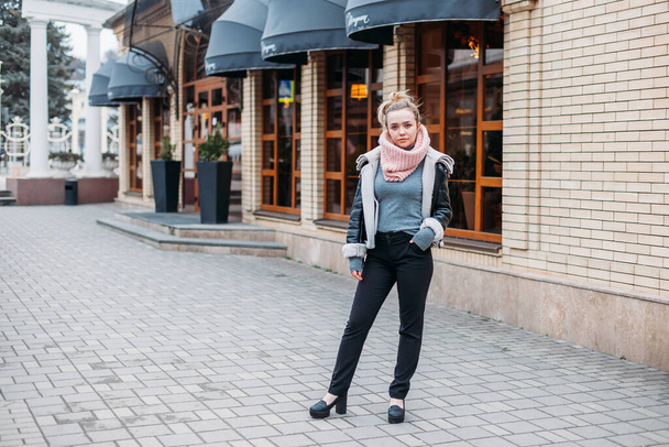 a young woman in a scarf poses on the streets of the city at a cafe - Photo, image