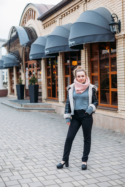 a young woman in a scarf poses on the streets of the city at a cafe - Фото, изображение
