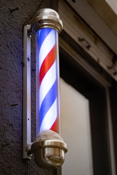 A barbers pole, unusual symbol of barbershops - Фото, изображение