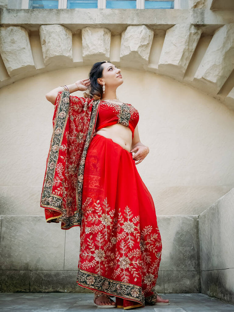 Indická žena tanec na ulicích starověké architektury města Indie oblečené v červené Sari, zdobené tradiční ozdoby a Mehendi vzory henna kresby na rukou. - Fotografie, Obrázek