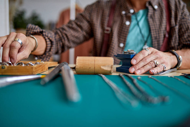 experienced young goldsmith working on a handmade jewelry in a workshop, cropped - Foto, immagini