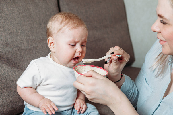 young mother feeds her son with a spoon of fruit puree - Foto, Bild