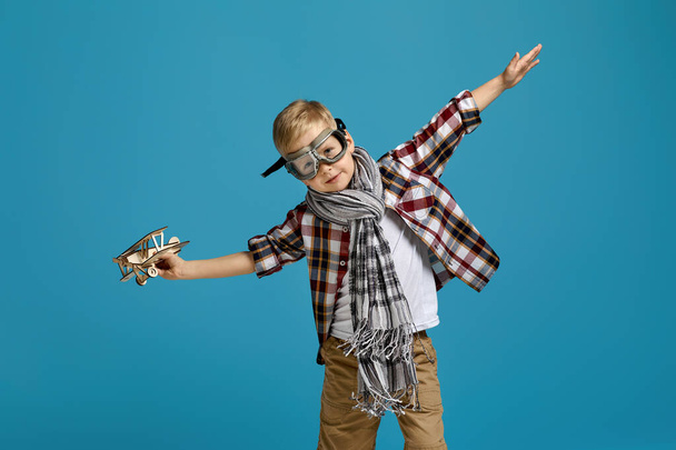 child boy in retro glasses playing with wooden toy airplane - Foto, Imagem