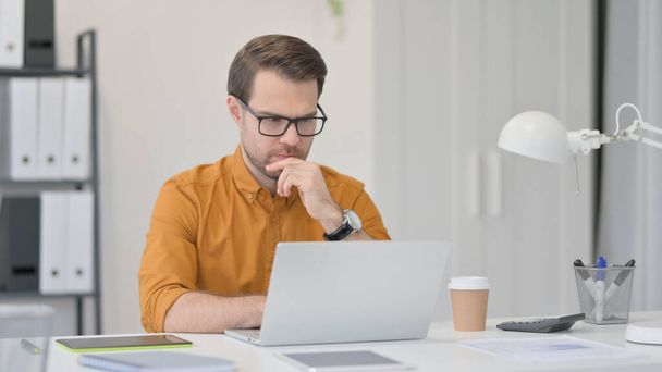Hombre joven con ordenador portátil, Pensando en la oficina  - Foto, imagen