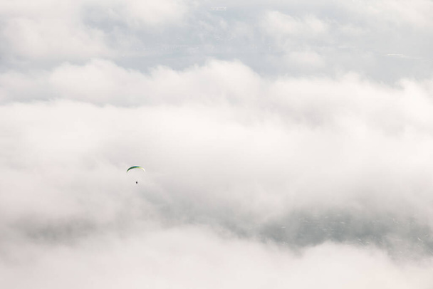 The paraglider flies in the air above the clouds against the backdrop of fluffy clouds. - Fotografie, Obrázek