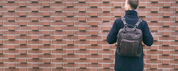 Banner trendy casual bearded man with leather backpack standing near brick wall. Stylish accessories, street wear, male city fashion. - Photo, Image